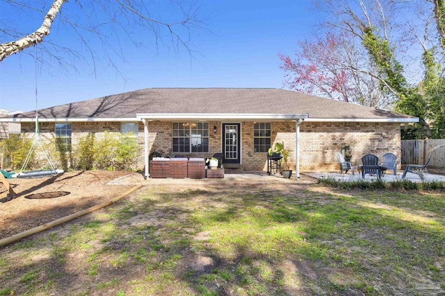 back of property with a shingled roof, a patio area, brick siding, and fence