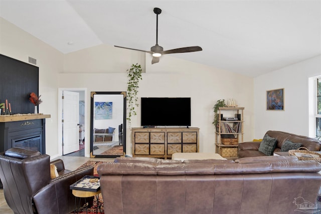 living area with lofted ceiling, visible vents, a ceiling fan, and a glass covered fireplace