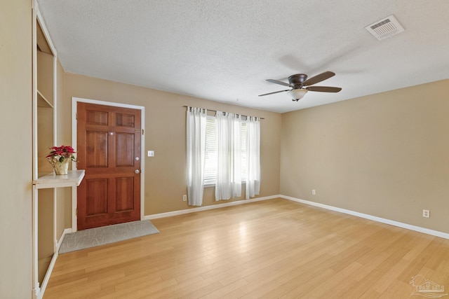 entryway with ceiling fan, light hardwood / wood-style flooring, and a textured ceiling