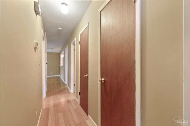 hall featuring a textured ceiling and light wood-type flooring