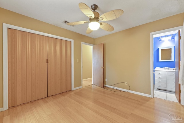 unfurnished bedroom with ensuite bathroom, sink, ceiling fan, light hardwood / wood-style floors, and a closet