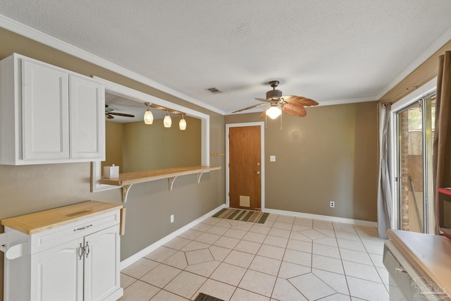 kitchen with ceiling fan, white cabinetry, a textured ceiling, light tile patterned floors, and ornamental molding