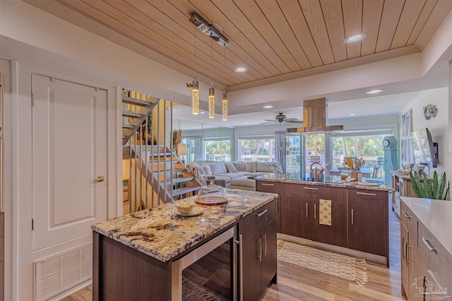 kitchen with wine cooler, a tray ceiling, light wood-style flooring, wood ceiling, and a kitchen island