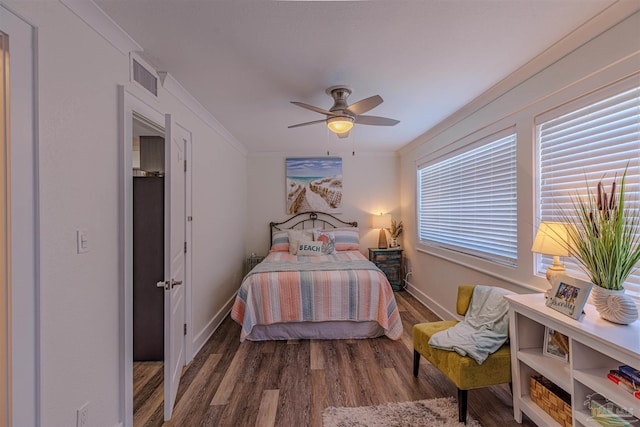 bedroom featuring visible vents, crown molding, baseboards, and wood finished floors