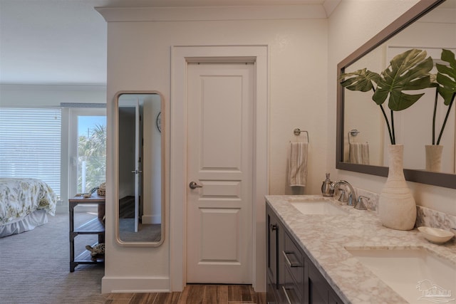 full bath featuring wood finished floors, double vanity, ornamental molding, and a sink