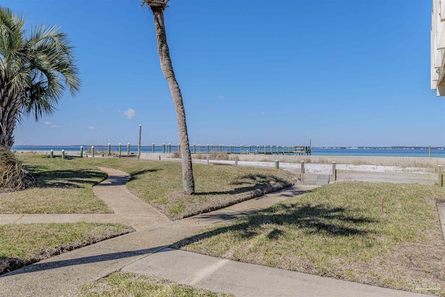 view of property's community with a lawn, a beach view, and a water view