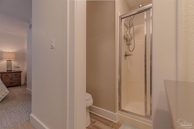 bathroom featuring toilet, a shower stall, baseboards, and a textured wall