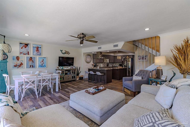 living area featuring dark wood-style floors, ornamental molding, a textured ceiling, and recessed lighting