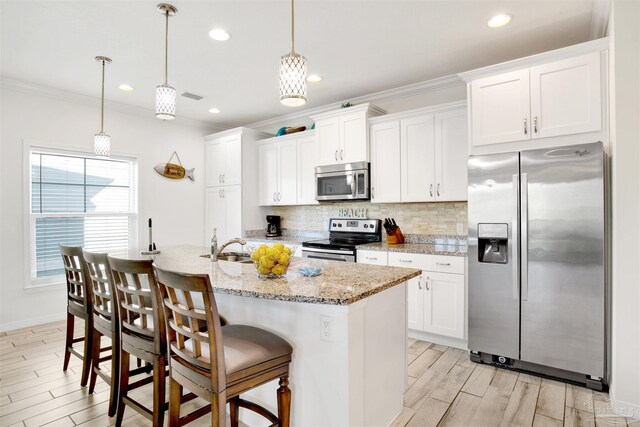 6548 Carlinga Dr, Pensacola, FL 32507 - kitchen featuring an island with sink, tasteful backsplash, light wood-type flooring, visible vents, and stainless steel appliances