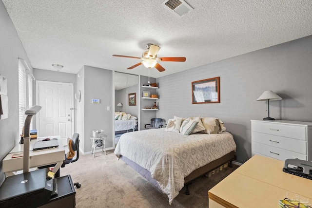 carpeted bedroom with ceiling fan and a textured ceiling