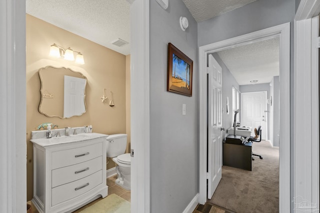 bathroom featuring vanity, toilet, and a textured ceiling