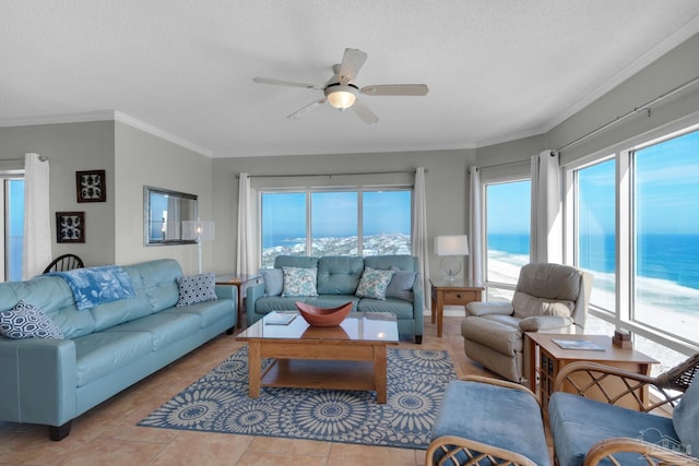 living room featuring ceiling fan, light tile patterned flooring, a textured ceiling, crown molding, and a water view