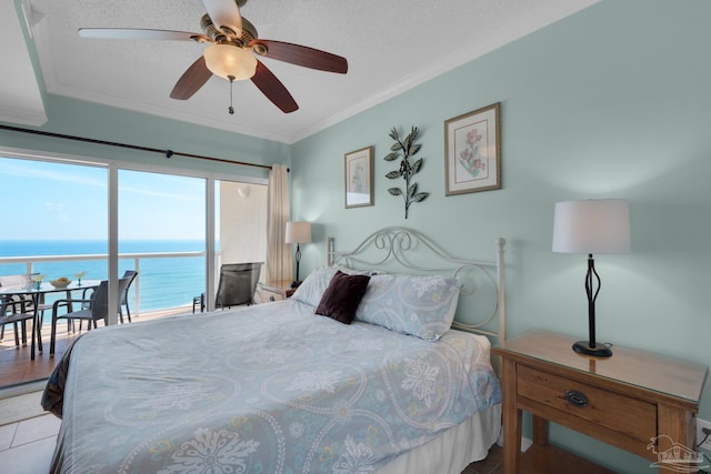 bedroom with ceiling fan, light tile patterned floors, ornamental molding, a textured ceiling, and a water view