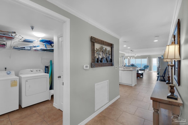 clothes washing area with ornamental molding, light tile patterned floors, and washer and dryer