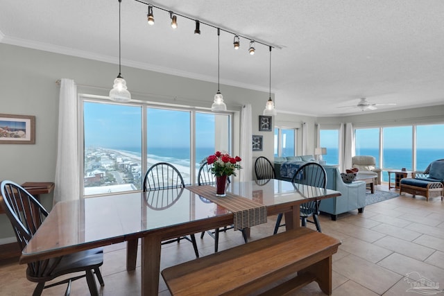 tiled dining space with ceiling fan, a textured ceiling, a water view, and a wealth of natural light