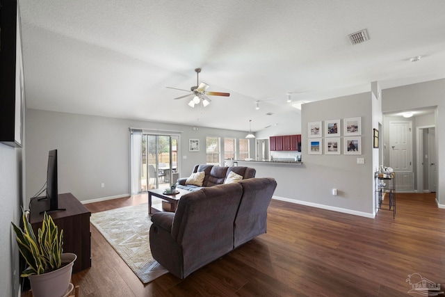 living room with a textured ceiling, ceiling fan, dark wood-type flooring, and lofted ceiling