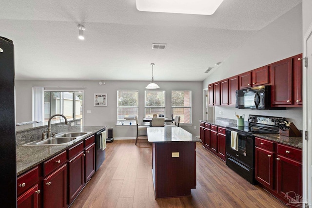 kitchen with vaulted ceiling, sink, black appliances, dark hardwood / wood-style floors, and a kitchen island