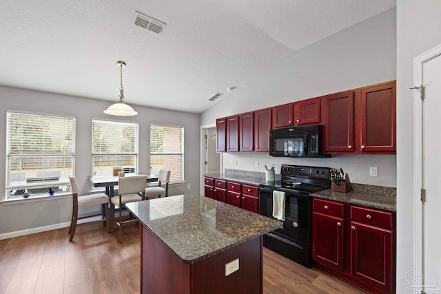 kitchen featuring dark hardwood / wood-style flooring, vaulted ceiling, black appliances, a center island, and hanging light fixtures