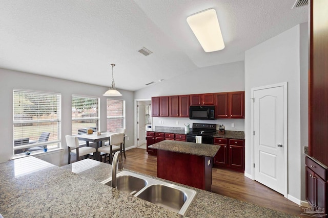 kitchen featuring a center island, black appliances, vaulted ceiling, decorative light fixtures, and dark hardwood / wood-style flooring