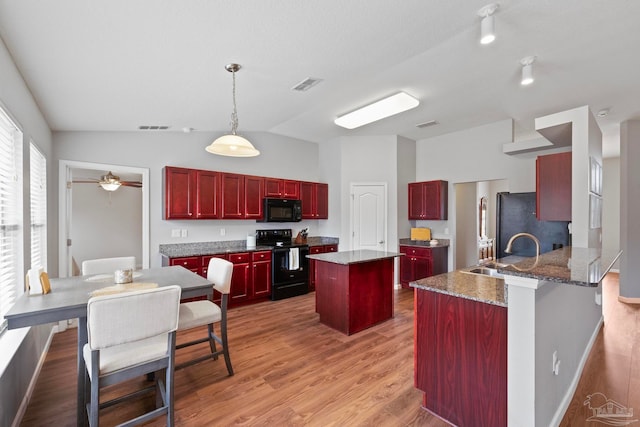 kitchen with pendant lighting, light hardwood / wood-style floors, lofted ceiling, and black appliances