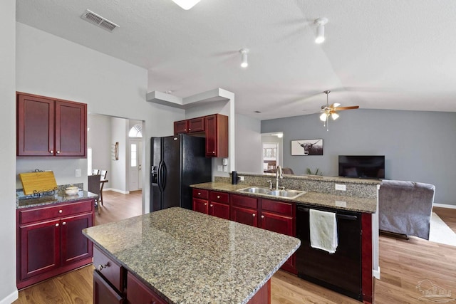 kitchen with sink, a kitchen island, black appliances, and vaulted ceiling