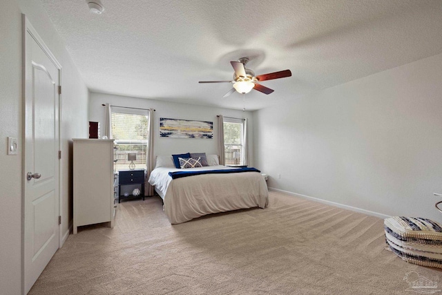 carpeted bedroom with multiple windows, ceiling fan, and a textured ceiling