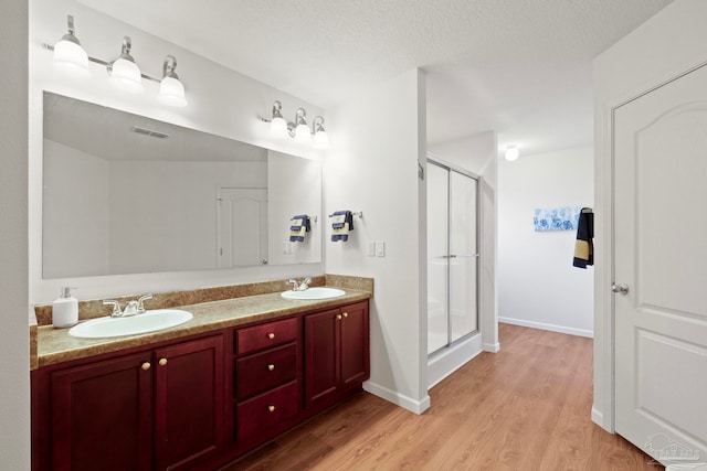 bathroom featuring wood-type flooring, vanity, a textured ceiling, and walk in shower