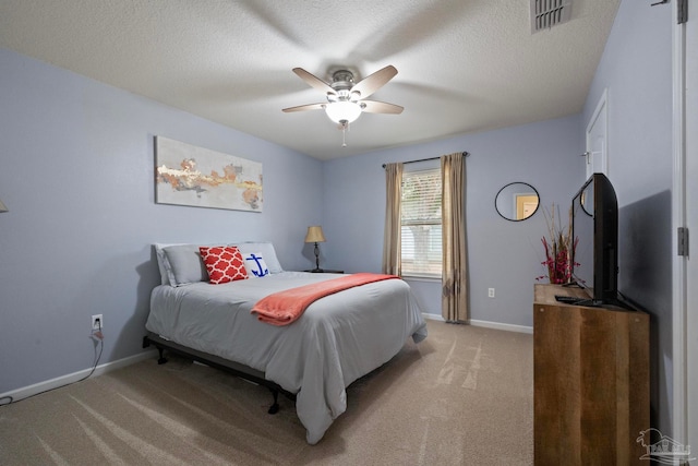 bedroom with ceiling fan, light colored carpet, and a textured ceiling