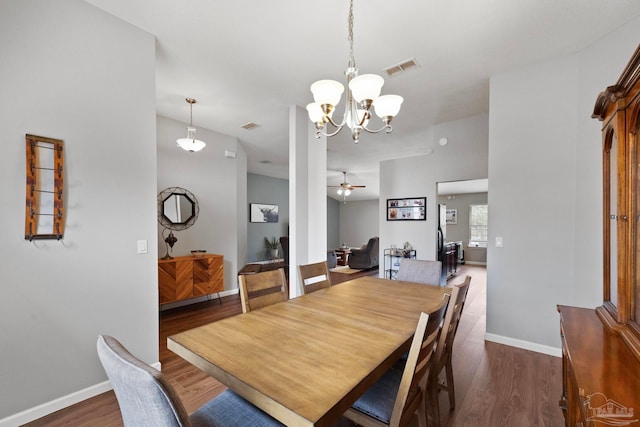 dining area with ceiling fan with notable chandelier and dark hardwood / wood-style flooring