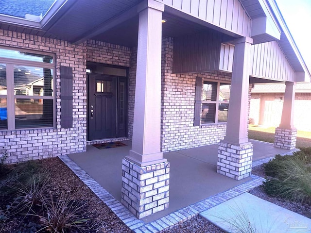 property entrance with board and batten siding, brick siding, and a porch