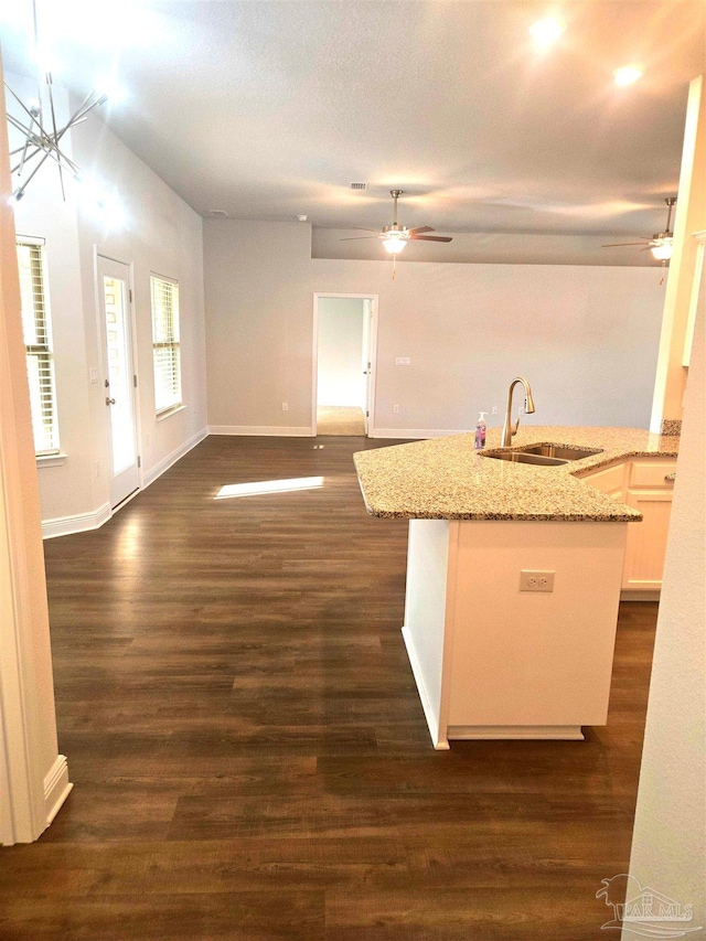 kitchen featuring an island with sink, white cabinetry, open floor plan, and a sink