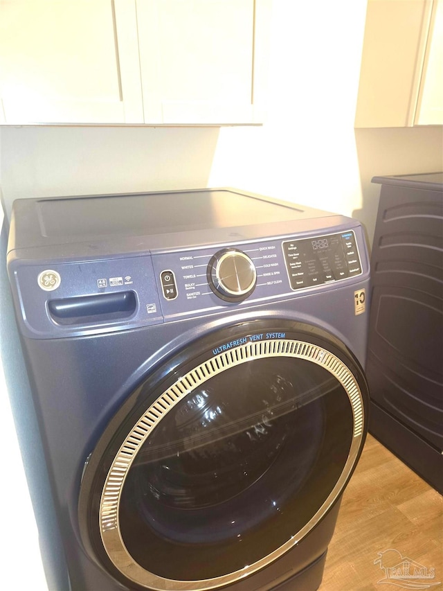 laundry area featuring cabinet space and light wood finished floors