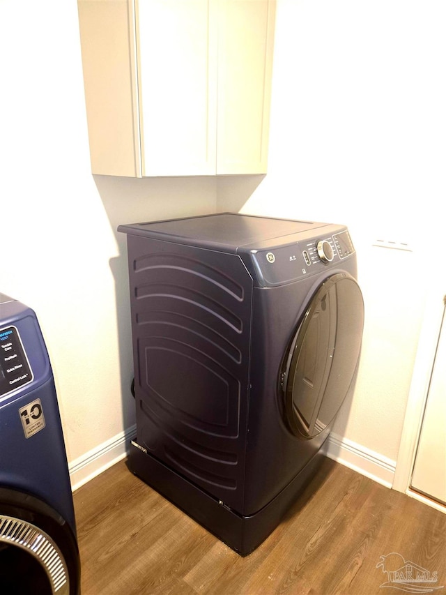 laundry area with washing machine and dryer, wood finished floors, cabinet space, and baseboards