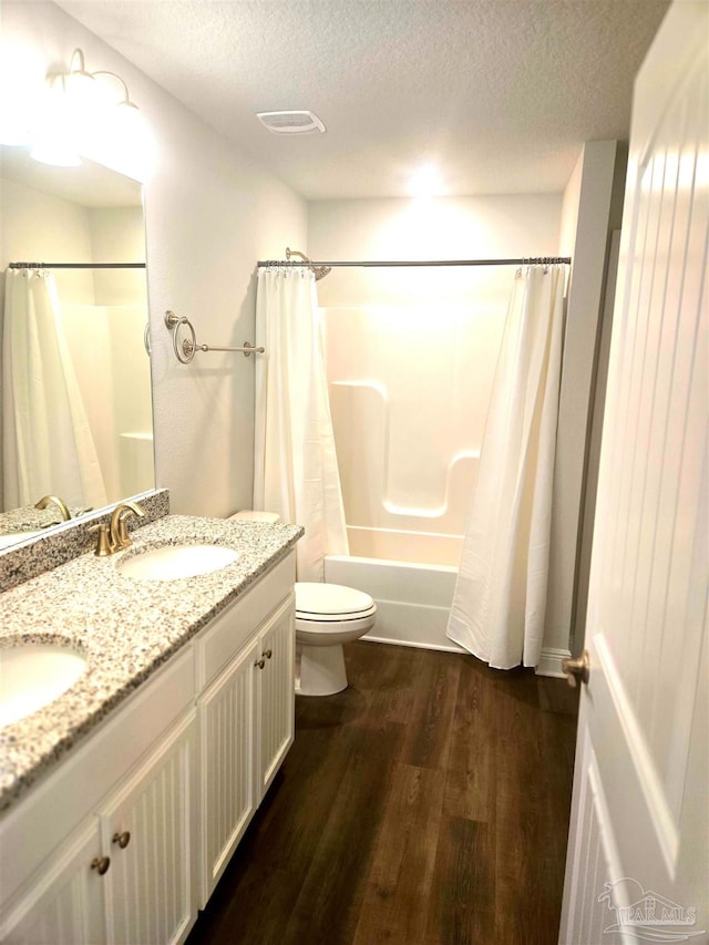 bathroom with wood finished floors, shower / tub combo, a textured ceiling, and a sink