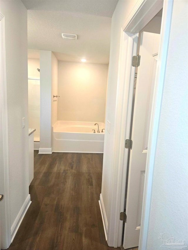 corridor featuring baseboards and dark wood finished floors