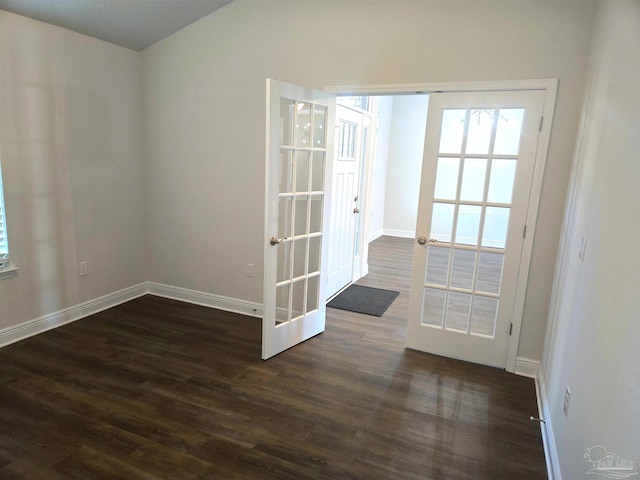 empty room featuring french doors, dark wood finished floors, and baseboards