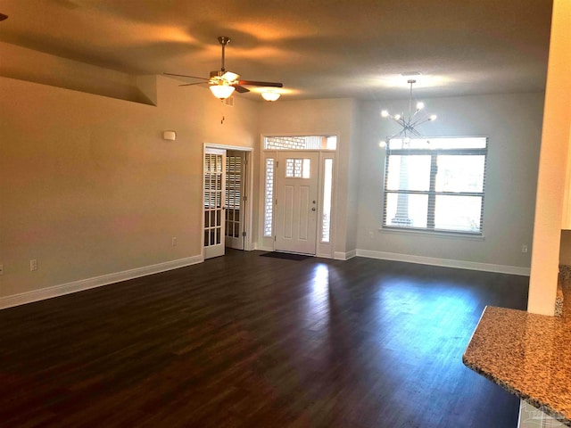 foyer entrance with dark wood-style floors, ceiling fan with notable chandelier, and baseboards