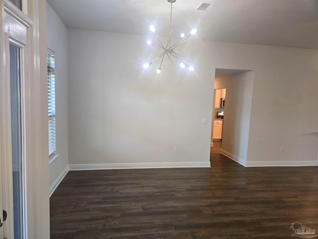 empty room featuring visible vents, dark wood finished floors, baseboards, and an inviting chandelier