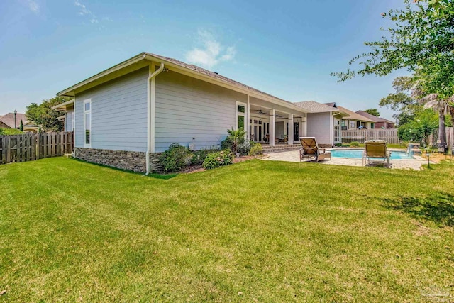 rear view of house with a fenced in pool, a lawn, a patio, and ceiling fan