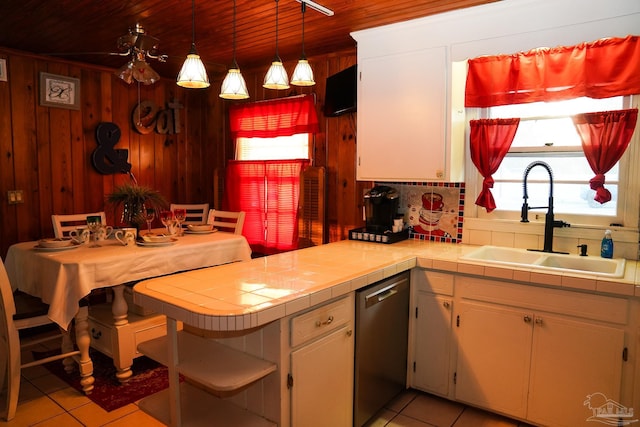 kitchen featuring tile countertops, stainless steel dishwasher, wooden ceiling, pendant lighting, and sink