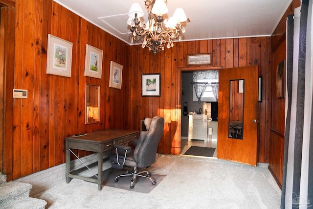 carpeted home office featuring wood walls, ornamental molding, and a chandelier