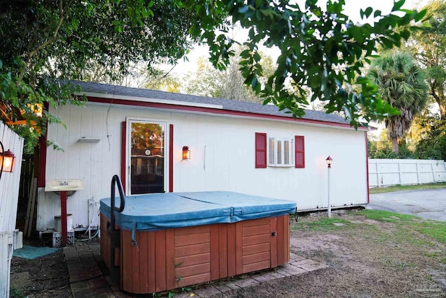 rear view of house with a hot tub and a patio