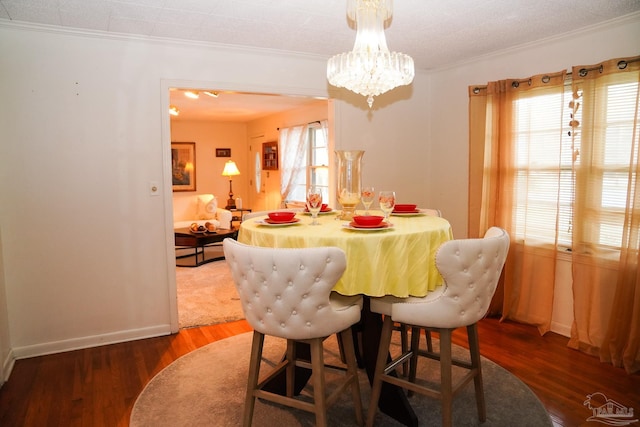 dining space featuring dark wood-type flooring, ornamental molding, and a textured ceiling