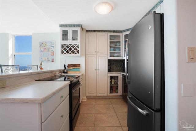 330FORT Pickens Rd Unit 11C, Pensacola Beach, FL 32561 - kitchen featuring light tile patterned floors, freestanding refrigerator, a peninsula, light countertops, and black range with electric cooktop