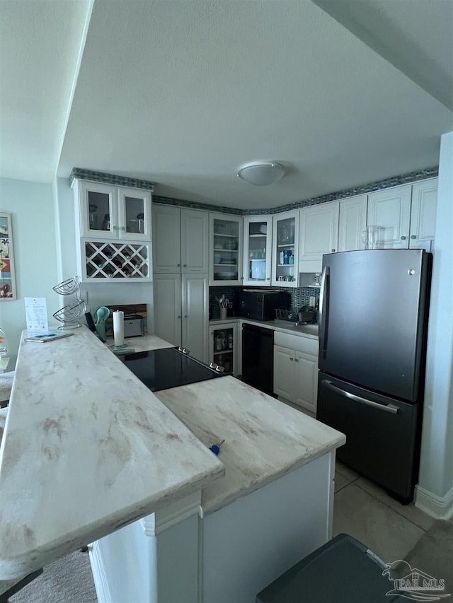 330FORT Pickens Rd Unit 11C, Pensacola Beach, FL 32561 - kitchen featuring dishwasher, freestanding refrigerator, a peninsula, white cabinetry, and light tile patterned flooring