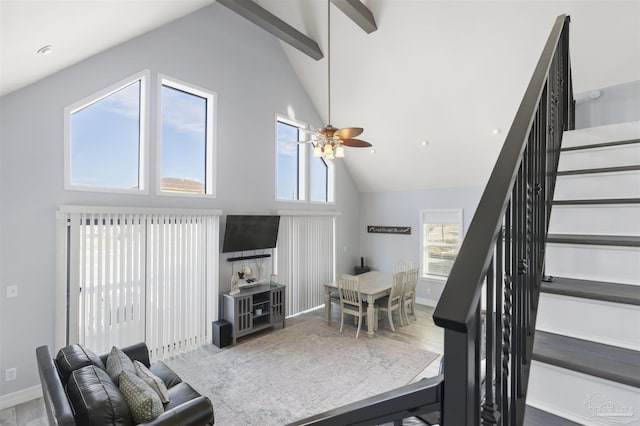 living room featuring beamed ceiling, high vaulted ceiling, ceiling fan, and a healthy amount of sunlight