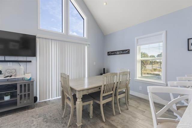 dining area featuring light hardwood / wood-style flooring and high vaulted ceiling