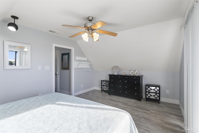 bedroom with ceiling fan, vaulted ceiling, and dark wood-type flooring