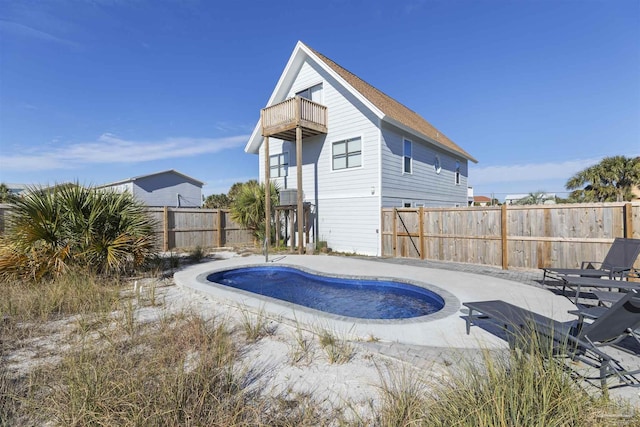 rear view of property with a balcony, a patio area, and a fenced in pool