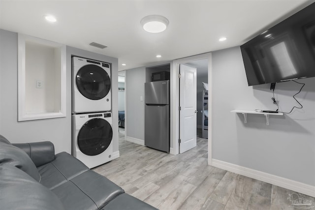 clothes washing area with stacked washer and clothes dryer and light hardwood / wood-style flooring